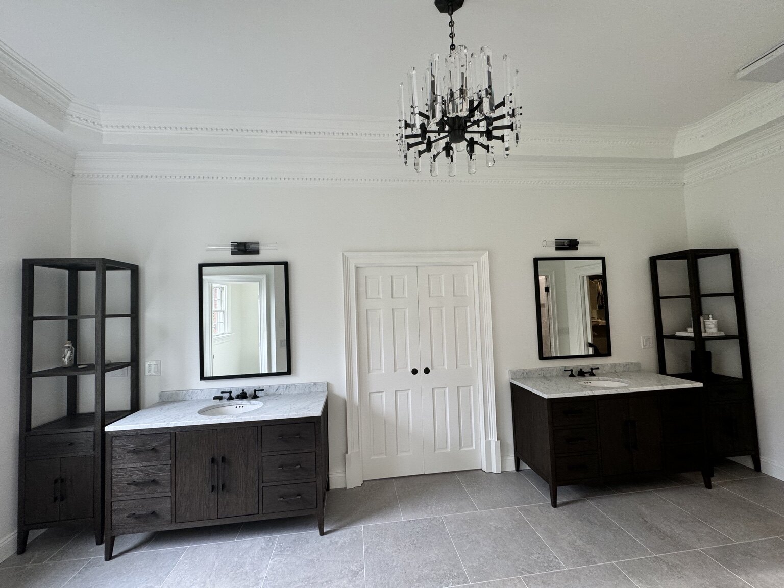 Bathroom after renovation with twin dark wood vanities and stone floor